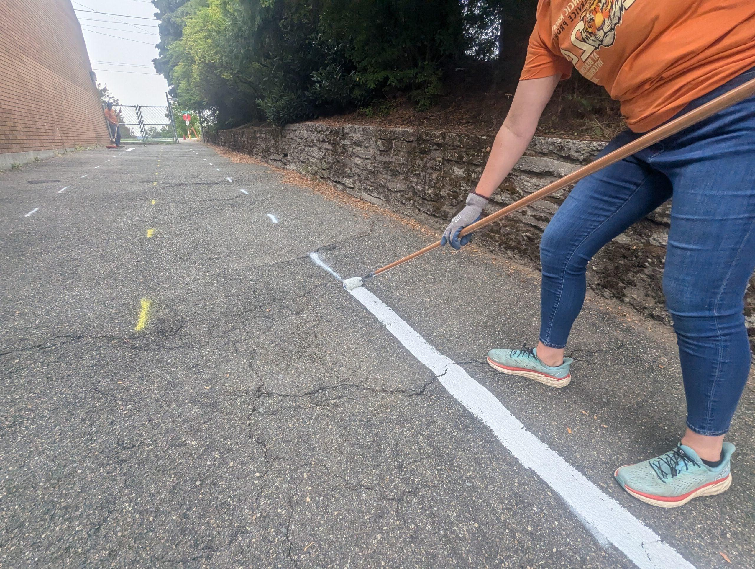 Volunteer painting street line for miniature traffic garden street.