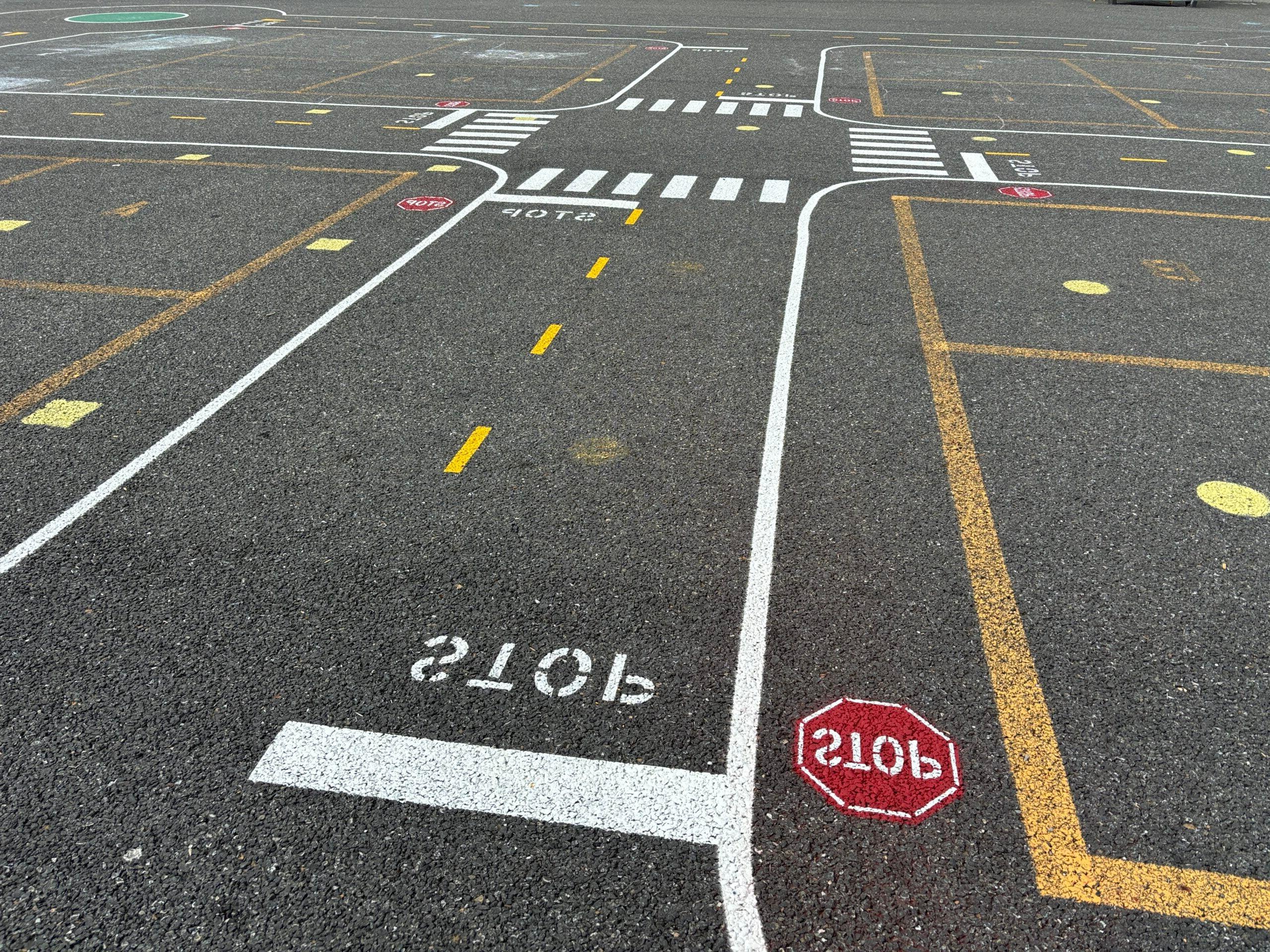 Miniature road painted on blacktop with stop sign.